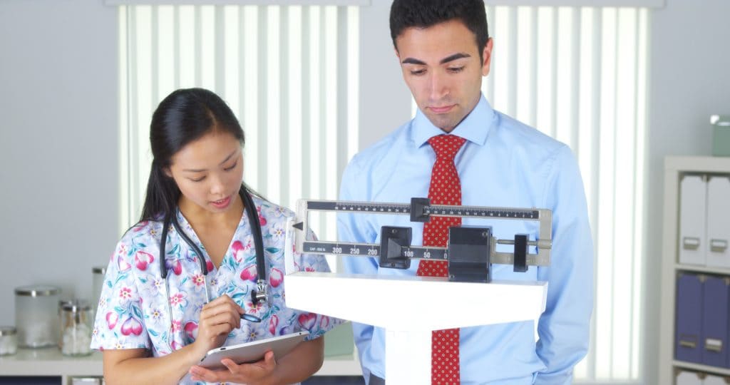 man standing on scale, weight loss, nurse with male patient
