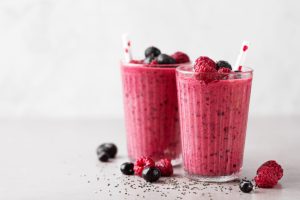Tasty healthy dieting red berry smoothie with chia seeds in glasses on grey background. Closeup with copy space.